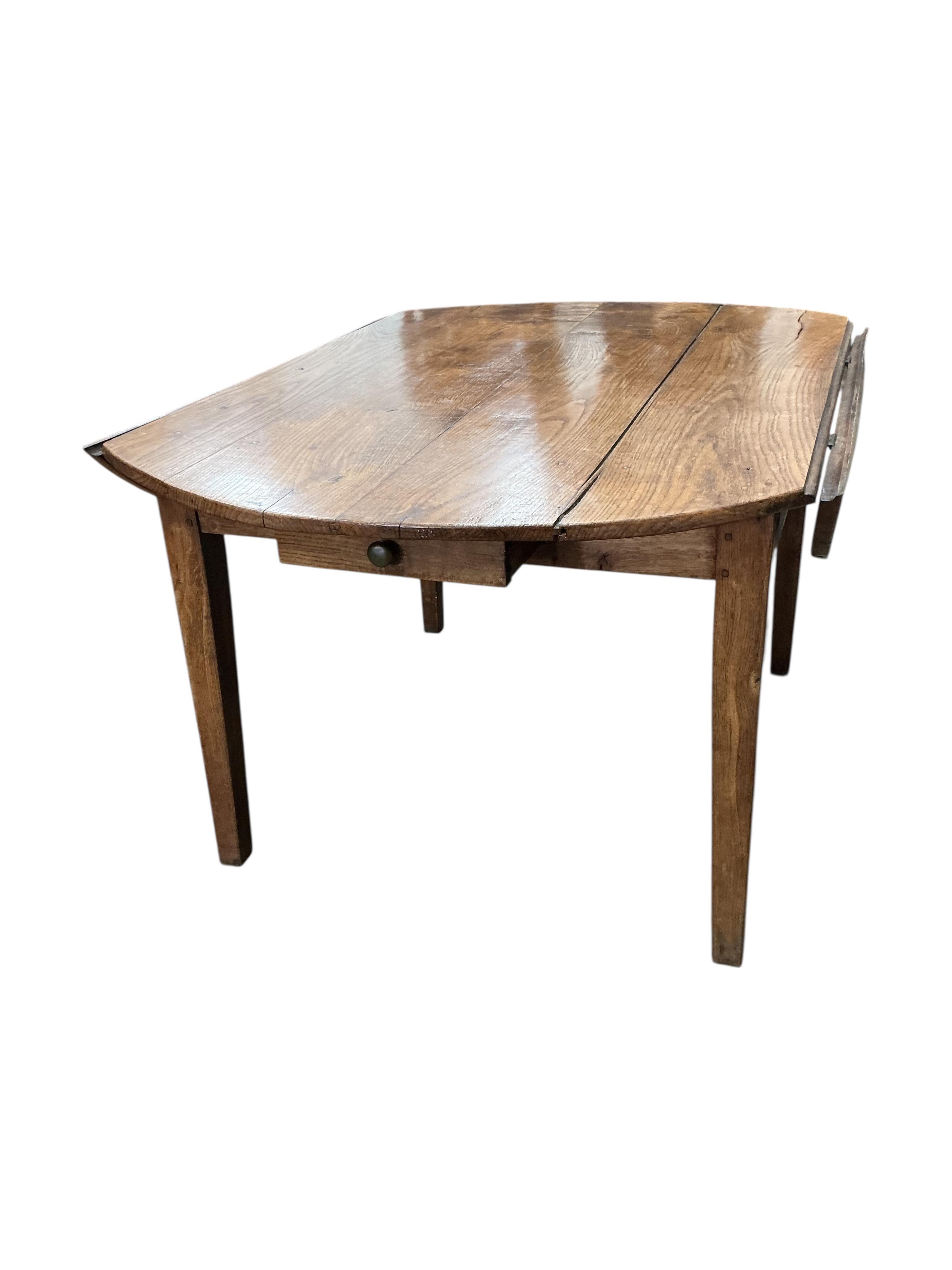 A 19th century French Provincial oak drop leaf dining table, diameter 138cm, extended, height 73cm